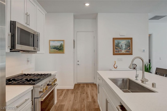 897 Woodburn Ln, Las Vegas, NV 89138 - kitchen featuring stainless steel appliances, light wood finished floors, light countertops, white cabinets, and recessed lighting