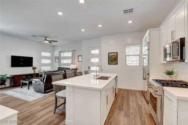 897 Woodburn Ln, Las Vegas, NV 89138 - kitchen with high quality appliances, light wood-style floors, an island with sink, ceiling fan, and light countertops