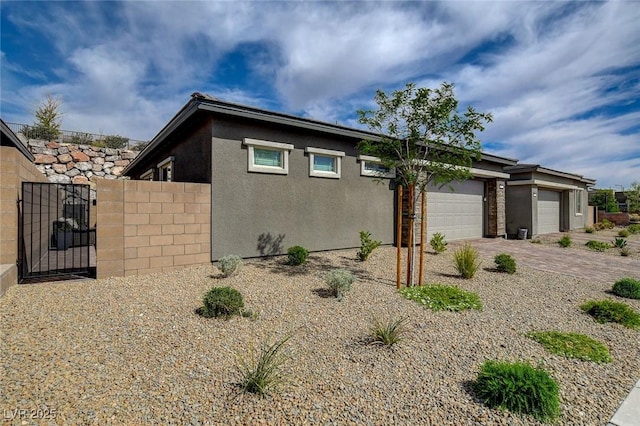 897 Woodburn Ln, Las Vegas, NV 89138 - view of home's exterior featuring a garage, driveway, stucco siding, and a gate