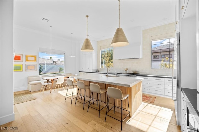 10969 Tranquil Waters Ct, Las Vegas, NV 89135 - kitchen featuring a sink, a breakfast bar, backsplash, a kitchen island with sink, and light wood-style flooring