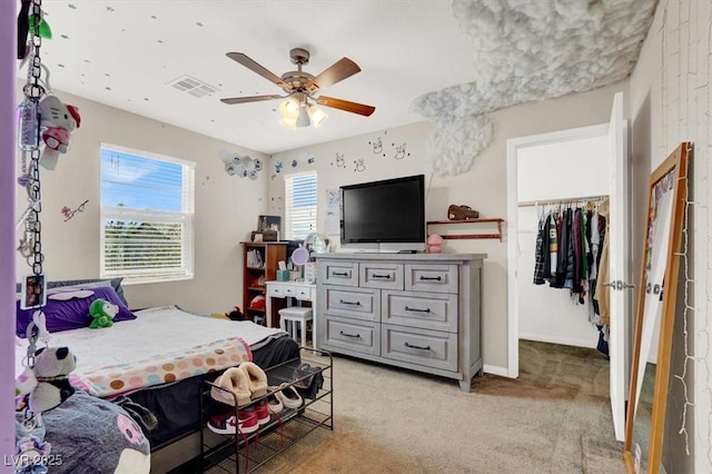 bedroom with a ceiling fan, a closet, a spacious closet, light colored carpet, and visible vents