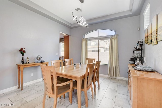 dining area with a tray ceiling, baseboards, and a chandelier
