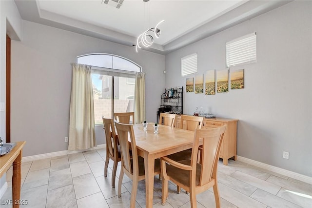 dining space with a tray ceiling and baseboards