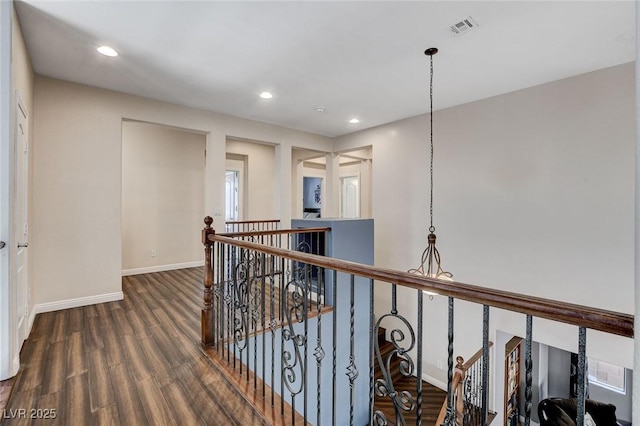 hallway with an upstairs landing, wood finished floors, baseboards, and recessed lighting