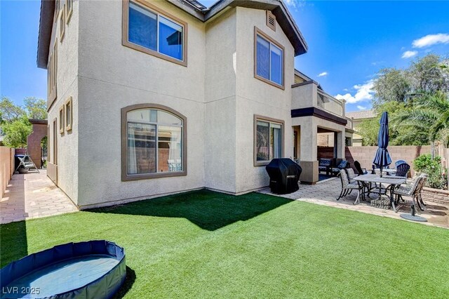 back of property with a balcony, stucco siding, and a patio