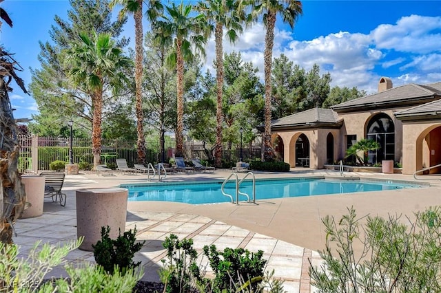 community pool with a patio area and fence