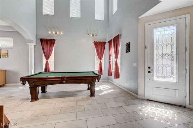 rec room with arched walkways, a high ceiling, pool table, baseboards, and tile patterned flooring