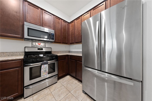 kitchen with dark brown cabinets, stainless steel appliances, light countertops, and light tile patterned flooring