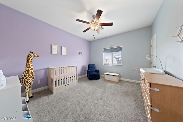 bedroom with a nursery area, baseboards, ceiling fan, and carpet
