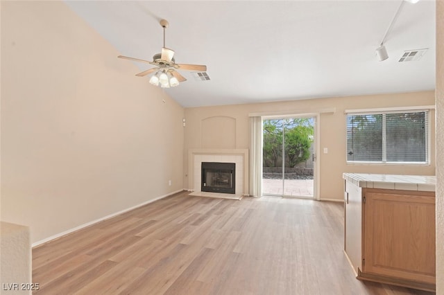 1805 Candle Bright Dr, Henderson, NV 89074 - unfurnished living room with a tile fireplace, light wood-type flooring, visible vents, and ceiling fan