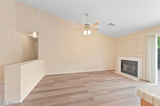 1805 Candle Bright Dr, Henderson, NV 89074 - unfurnished living room with vaulted ceiling, a ceiling fan, light wood-style floors, a tiled fireplace, and visible vents