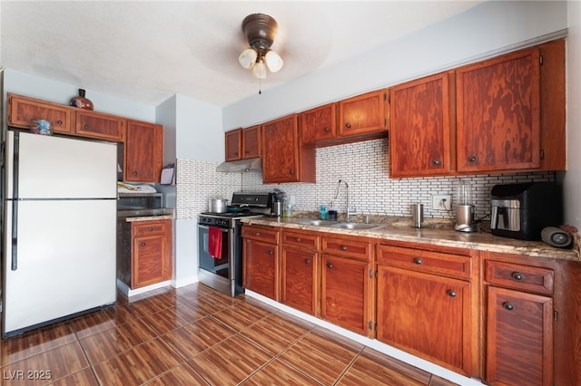 kitchen with appliances with stainless steel finishes, a sink, under cabinet range hood, ceiling fan, and backsplash