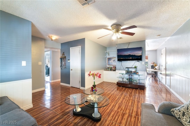 living room featuring ceiling fan, a textured ceiling, and wood finished floors