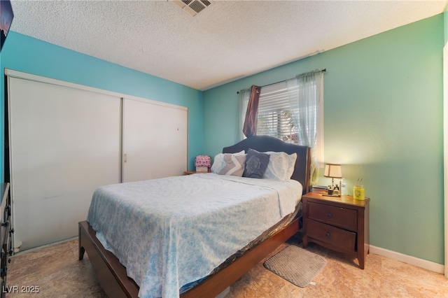 bedroom with a textured ceiling, a closet, and baseboards