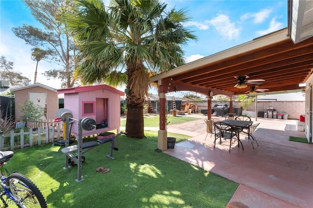 view of yard with a storage shed, ceiling fan, a patio area, and an outdoor structure