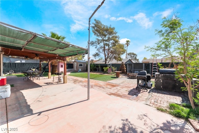 view of patio featuring a storage unit, an outbuilding, a fenced backyard, and outdoor dining space