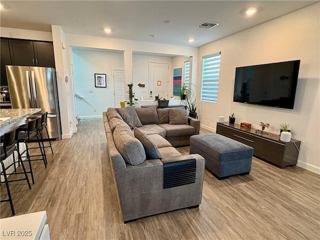 living area featuring light wood-style floors, baseboards, and recessed lighting