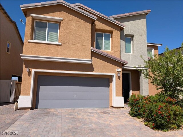 view of front of home with stucco siding, a tiled roof, fence, and a garage