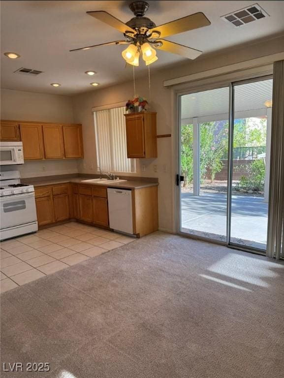 kitchen with visible vents, white appliances, light colored carpet, and a sink
