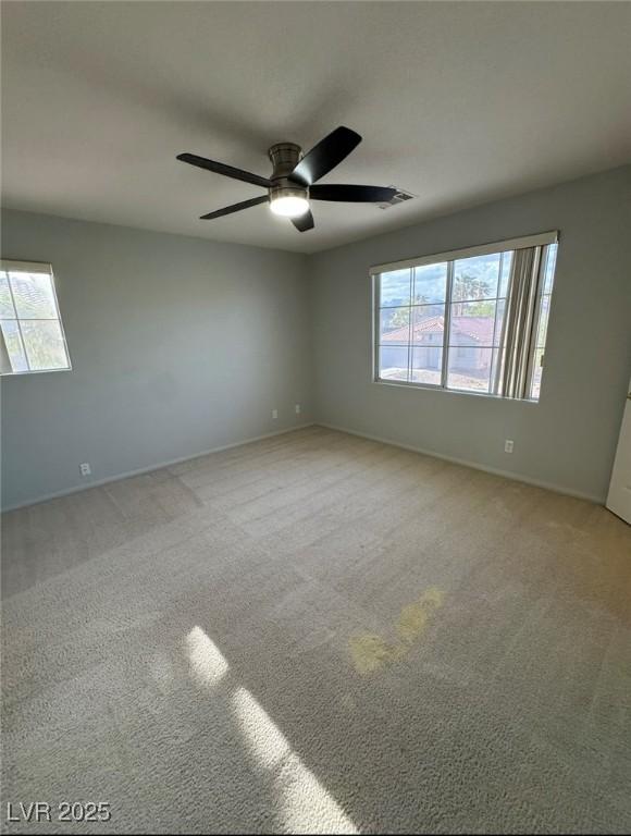 empty room featuring baseboards, a healthy amount of sunlight, carpet, and ceiling fan