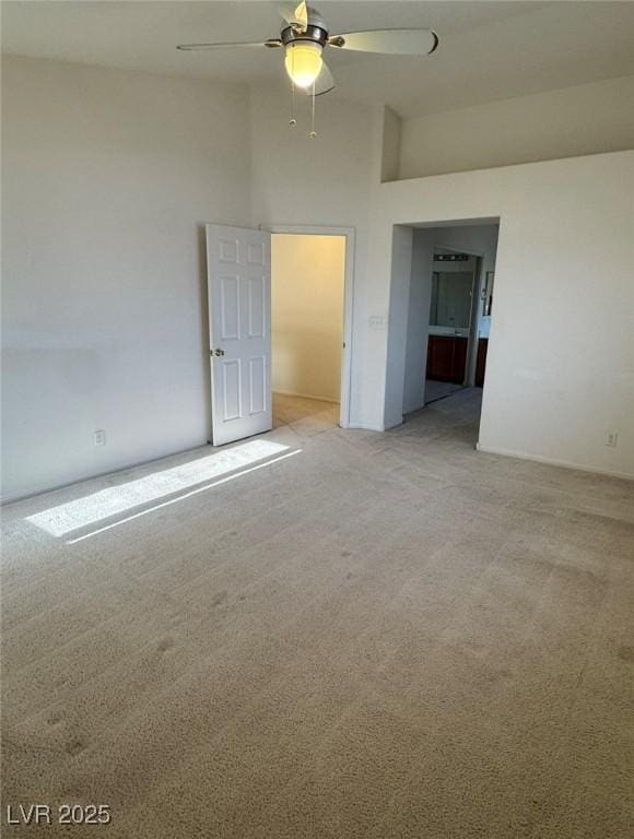 spare room featuring light carpet, ceiling fan, and a towering ceiling