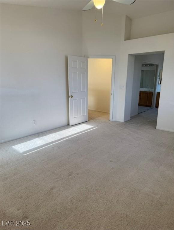 unfurnished bedroom with a towering ceiling, a ceiling fan, and light carpet