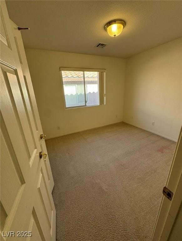 spare room featuring visible vents and light carpet
