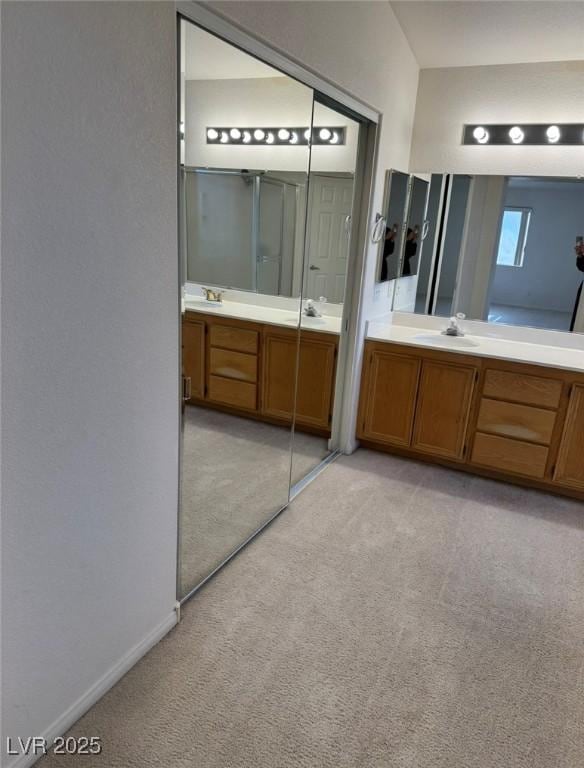 bathroom featuring baseboards, two vanities, carpet flooring, and a sink