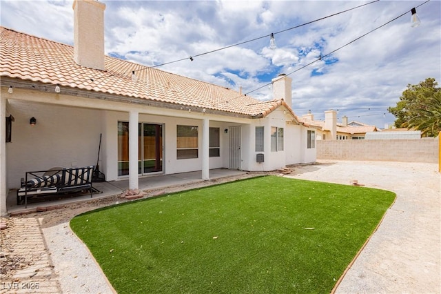rear view of house featuring fence, stucco siding, a chimney, a patio area, and a tile roof