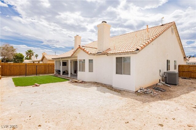 rear view of property with central air condition unit, a tile roof, a fenced backyard, and stucco siding