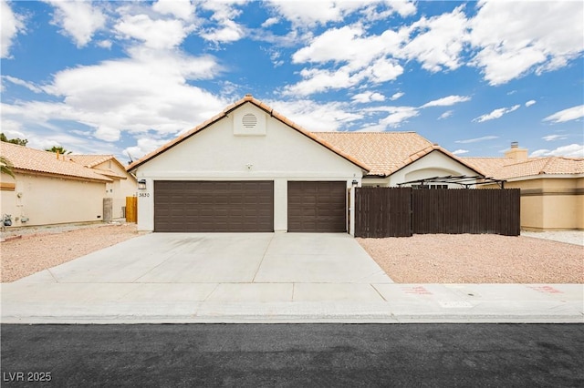 view of front facade with a tiled roof, a garage, fence, concrete driveway, and stucco siding