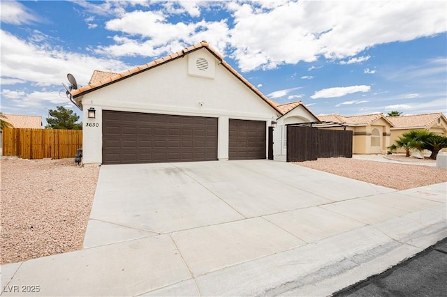 view of front of property with an attached garage, stucco siding, driveway, and fence