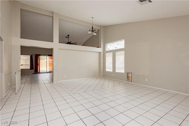 empty room with baseboards, a ceiling fan, light tile patterned flooring, and high vaulted ceiling