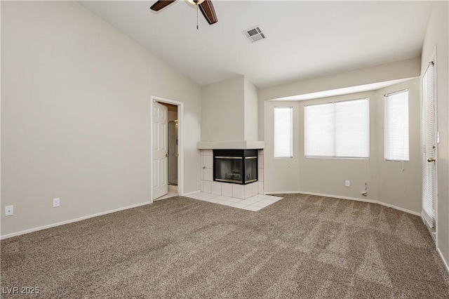 unfurnished living room with light colored carpet, a ceiling fan, vaulted ceiling, a tile fireplace, and visible vents