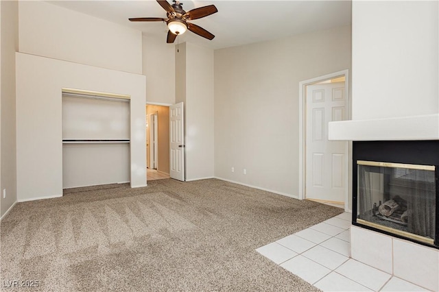 unfurnished living room with a multi sided fireplace, ceiling fan, baseboards, high vaulted ceiling, and carpet flooring