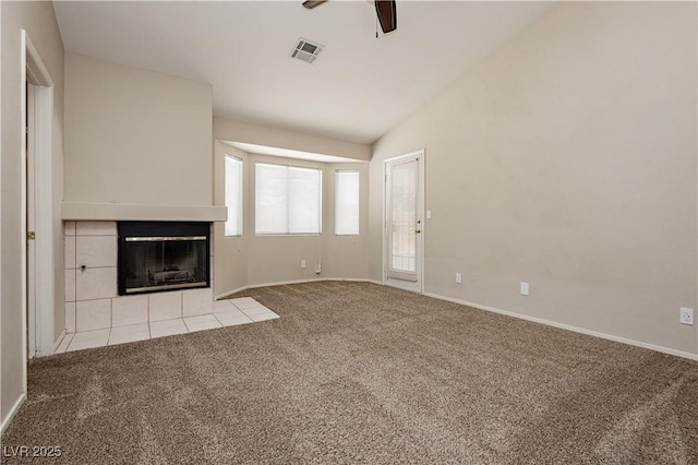 unfurnished living room featuring visible vents, a ceiling fan, lofted ceiling, a tiled fireplace, and carpet flooring