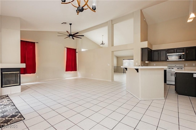 kitchen featuring gas range gas stove, open floor plan, light countertops, stainless steel microwave, and dark cabinetry