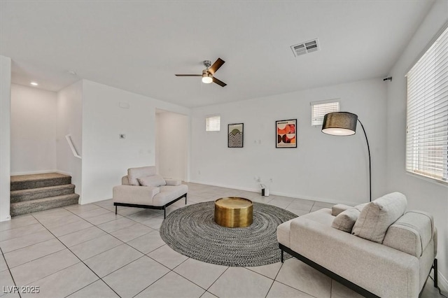 living area featuring a ceiling fan, light tile patterned flooring, stairs, and visible vents