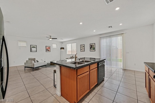 kitchen featuring dark countertops, a sink, open floor plan, light tile patterned floors, and black dishwasher