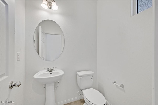 half bath with toilet, baseboards, and a sink