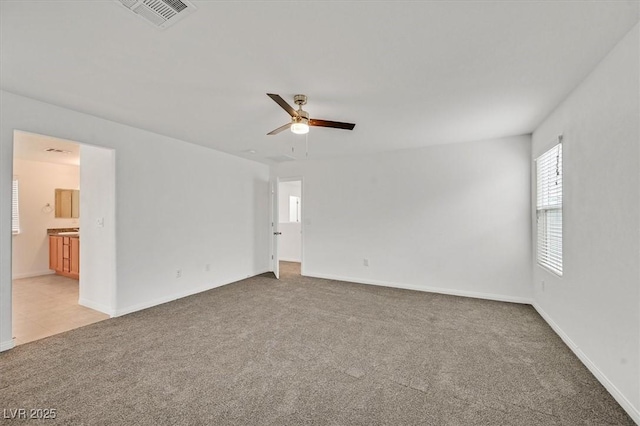 unfurnished room featuring ceiling fan, light carpet, visible vents, and baseboards