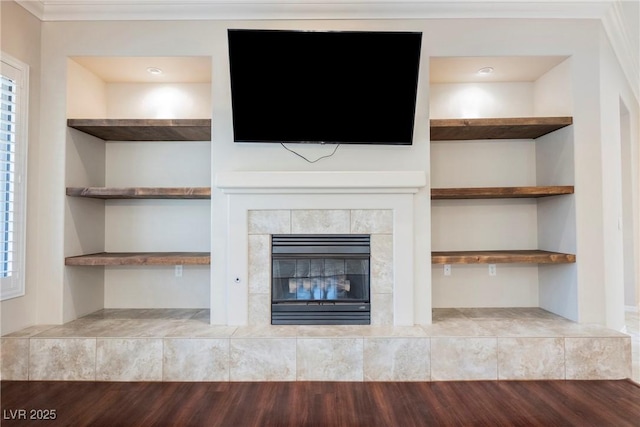 unfurnished living room featuring ornamental molding, a tiled fireplace, and wood finished floors