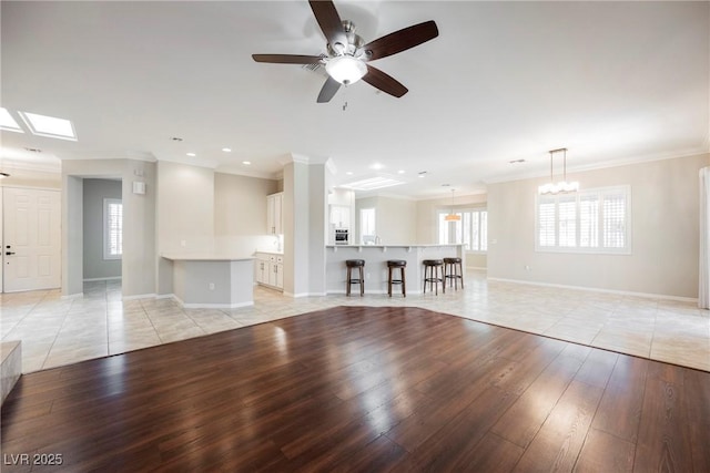 unfurnished living room with recessed lighting, ceiling fan, crown molding, light wood-style flooring, and baseboards