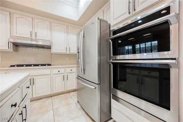 kitchen with light tile patterned floors, white cabinetry, stainless steel appliances, light countertops, and under cabinet range hood