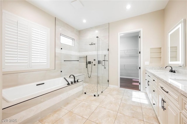 full bathroom with tile patterned flooring, double vanity, a bath, a walk in closet, and a stall shower