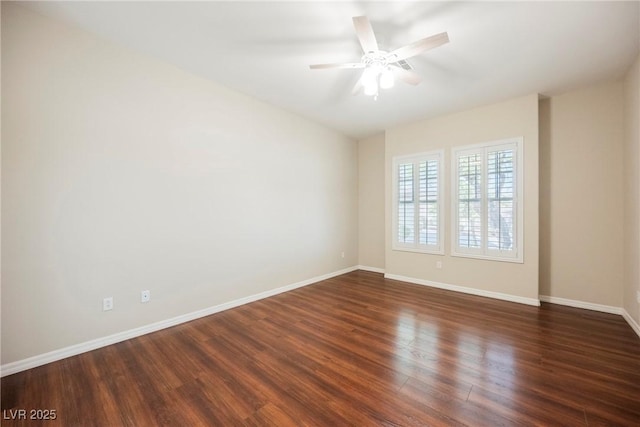 spare room featuring dark wood-style floors, ceiling fan, and baseboards