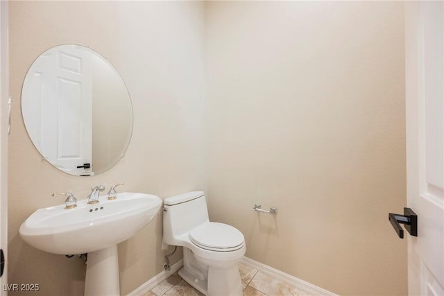 half bathroom with toilet, tile patterned flooring, and baseboards