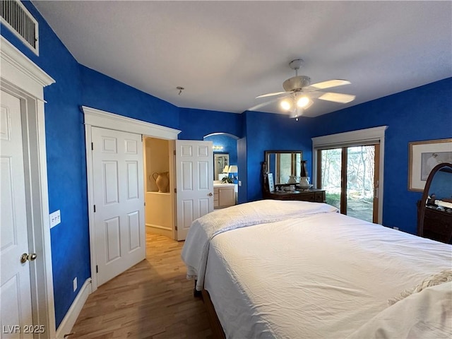 bedroom featuring access to exterior, visible vents, arched walkways, wood finished floors, and baseboards