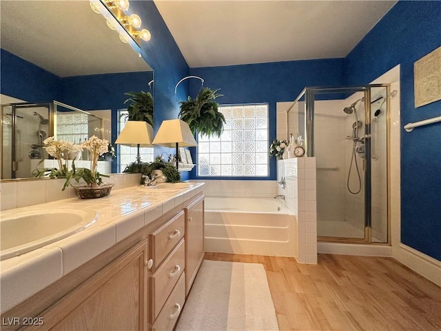 bathroom with a garden tub, a stall shower, and wood finished floors