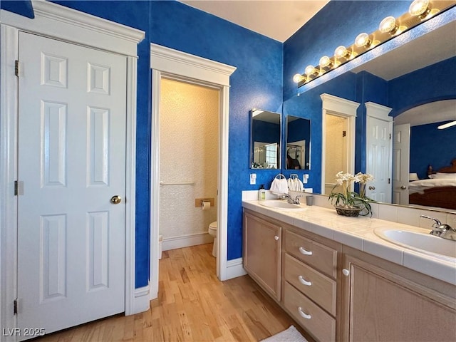 bathroom featuring a sink, baseboards, toilet, and wood finished floors
